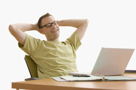 Man leans back in his chair while working on his laptop at home.  Horizontal shot.  Isolated on white.の写真素材