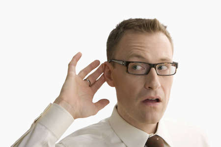 A businessman has his hand by his ear to gesture that he can't hear.  Horizontal shot.  Isolated on white.の写真素材