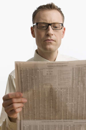 A businessman intently reads the newspaper.  Vertical shot.  Isolated on white.の写真素材