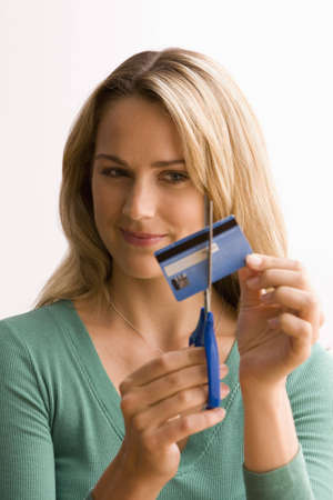 A young woman is cutting through her credit card with scissors.  Vertical shot.の写真素材