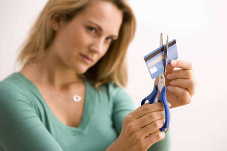 A young woman is cutting through her credit card with scissors.  Vertical shot.の写真素材