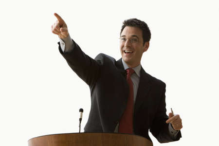 A young businessman is standing at a podium and pointing. Horizontal shot. Isolated on white.の写真素材
