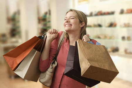 Beautiful young woman shows an ecstatic expression while holding shopping bags in a store.  Horizontal shot.の写真素材