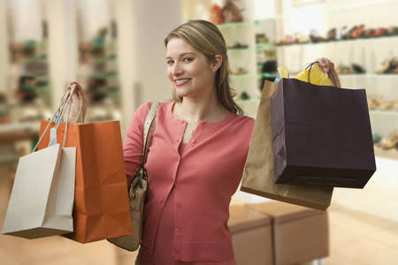 Beautiful young woman shows an ecstatic expression while holding shopping bags in a store. ...