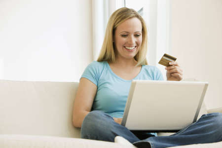 A young woman is working on a laptop and holding up her credit card.  Horizontal shot.の写真素材