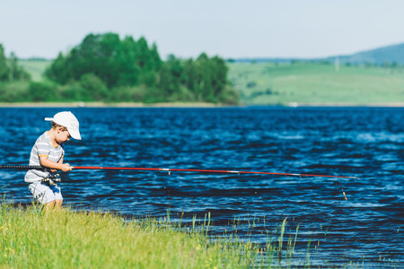 Little boy trying to handle fishing rodの写真素材
