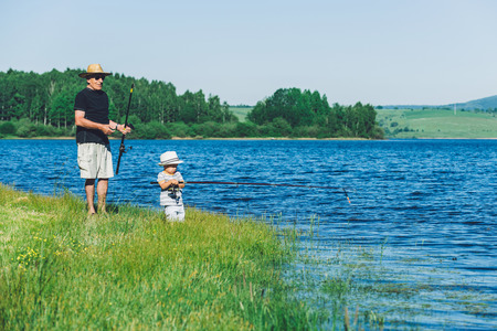 Grandfather with grandson have fun fishing on the lakeの写真素材