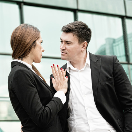 Sexual harassment at work - manager in aggressive stance towards younger female coleagueの写真素材