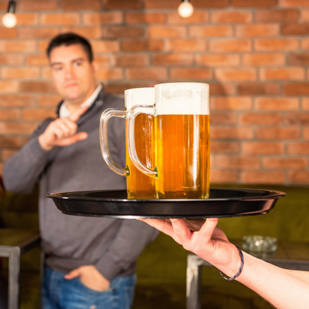 Ordering beer in pub. Focus on mugs, blurred backgroundの写真素材