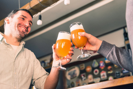 Positive smiling friends drinking beer, having fun in barの写真素材