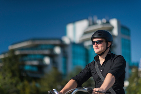 Young businessman on electric bicycle in business centerの写真素材