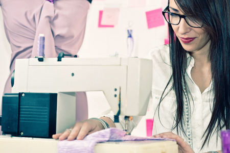 Fashion designer working with sewing machine. Toned image