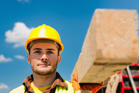Construction worker carrying wooden beamの写真素材