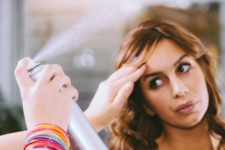 Spraying hair with hairsprayの写真素材