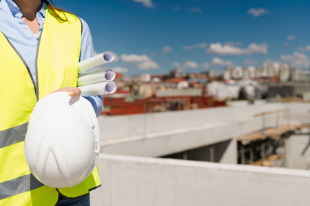 Architect with plans and hardhat on a construction siteの写真素材