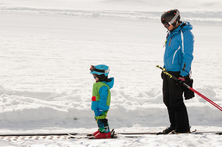 Ski trainer and little boy skiing downhillの写真素材