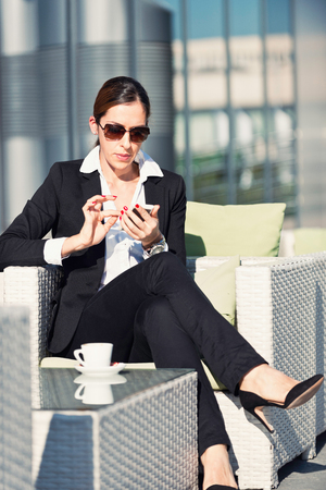 Businesswoman at coffee break, using smart phoneの写真素材