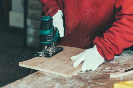Carpenter cutting through wooden plank with power sawの写真素材