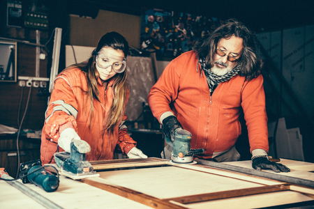 Small family business - Father doing carpentry work with his daughterの写真素材