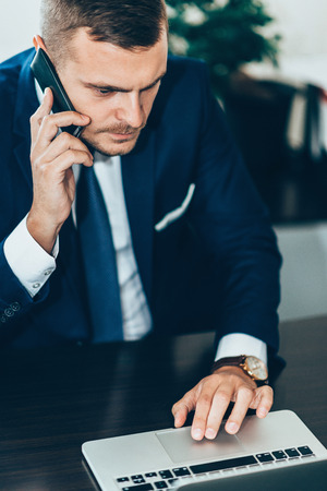 Businessman talking over the phone in his officeの写真素材