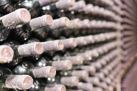 Detail from huge wine cellar. Racks with thousands of wine bottles covered in dust. Selective focus set on bottles close to cameraの写真素材