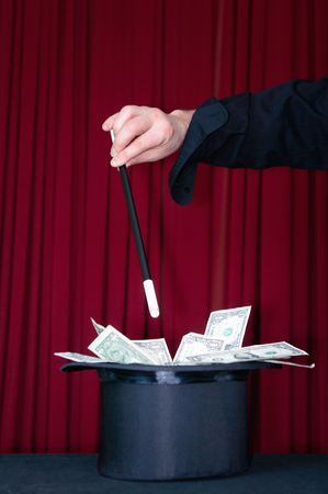 Stage magician fills his top hat with dollarsの写真素材