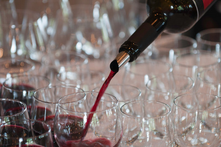 Pouring red wine at a cocktail party.