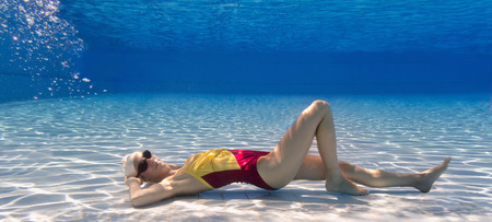 Young synchronized swimmer laying on back on the bottom of swimming poolの写真素材