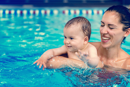 Cute baby boy enjoying with his mother in the pool.の写真素材