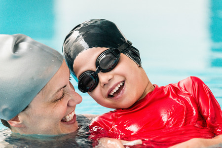 Cute boy enjoying in the swimming pool with his motherの写真素材
