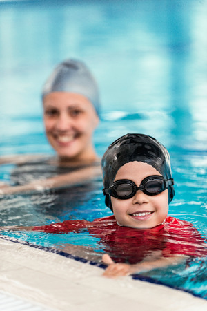 Happy child in the swimming pool, instructor behindの写真素材