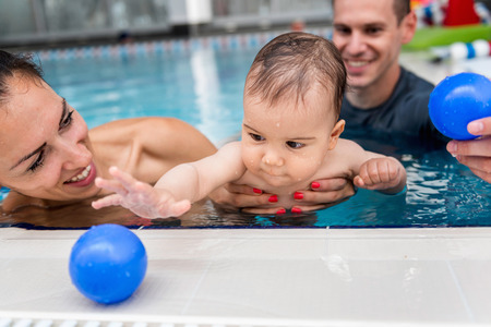 Instructor with baby boy and his mother playing in the pool.の写真素材