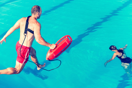 Lifeguard rescue course - lifeguard jumping towards victim. Toned imageの写真素材