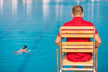 Lifeguard on duty, sitting in lifeguard chair, overlooking pool. Polarizing filterの写真素材