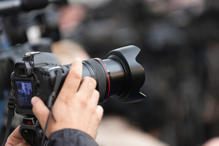 TV reporter photographing in press roomの写真素材