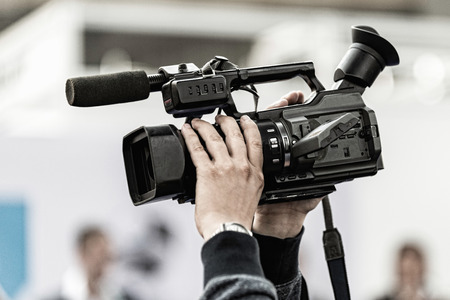 Cameraman holding tv camera high above