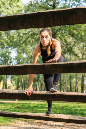 Female athlete crossing wooden barriers on a obstacle course in parkの写真素材