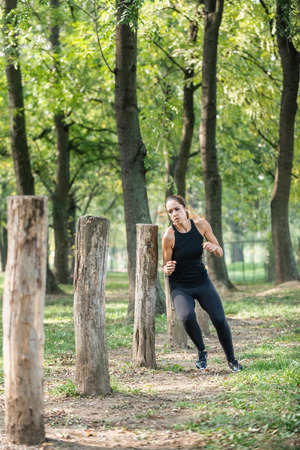 Female athlete running around logs on fitness trailの写真素材
