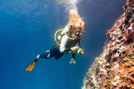 Female diver underwater with torchの写真素材