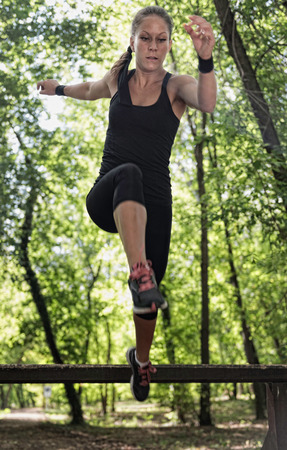 Female athlete crossing wooden barriers on fitness trailの写真素材