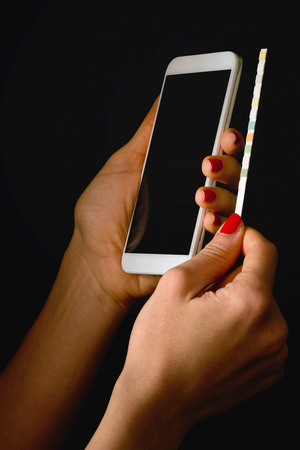Personal mobile heathcare app - Patient analyzing results with smart phone and indicator paper stripの写真素材