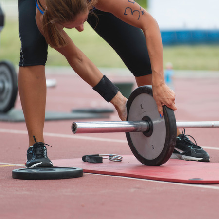 Female CrossFit competitor changing weights on weightlifting barの写真素材
