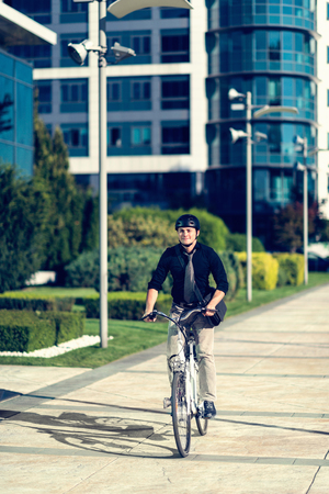 Young man using electric bicycle in modern cityの写真素材