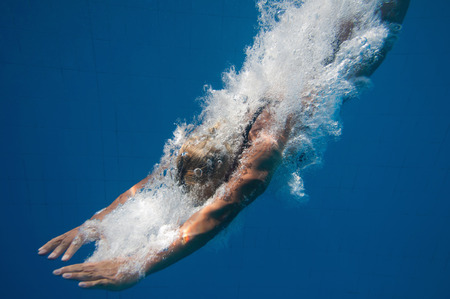 Close up underwater shot of a young woman entering the poolの写真素材