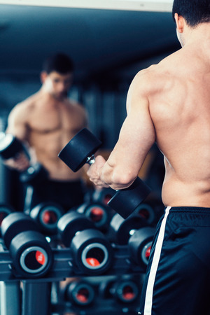 Muscular man exercising in the gym in front of mirrorの写真素材