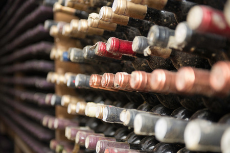 Bottles of wine aging in a cellar. Selective focus, all   and identifying marks removed