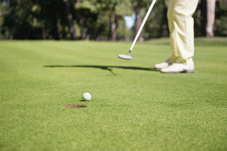 Golfer plays perfect putting shot. Very shallow depth of field with moving ball in focus.の写真素材
