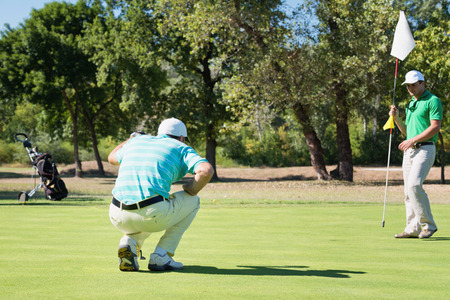 Golfer and caddy on putting green during the gameの写真素材