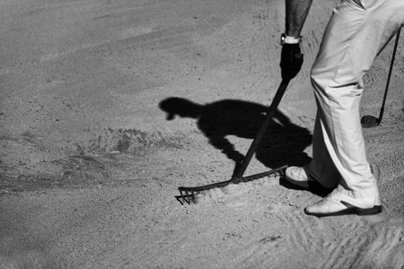 Golfer raking sand trapの写真素材