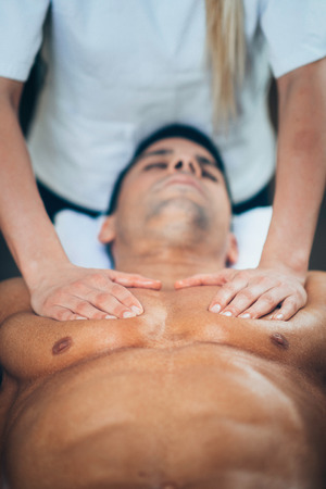 Sports massage - Chest massage - Physical therapist doing massage of chest. Toned image, selective focus set on chest and hands.の写真素材